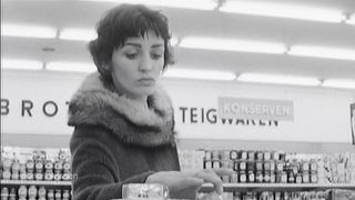 Schwarzweißaufnahme einer jungen Frau in einem Supermarkt der 1960er Jahre.