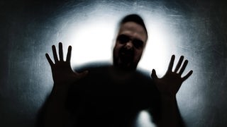Ein Mann mit ausgestreckten Fingern nur dunkel zu erkennen vor einem hellen Hintergrund.