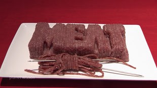 Laborfleisch zum Schriftzug 'Meat' geformt auf eine weißen Schale.
