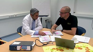 Dr. Martin Schiffarth sitzt mit einem anderen Arzt an einem Besprechungstisch.