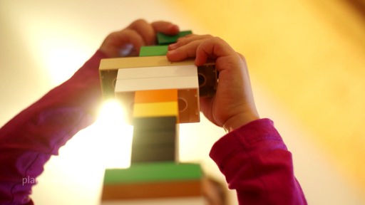 Kinderhände beim Bauen eines Legoturms
