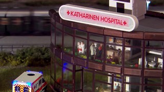 Modell eines Krankenhauses auf dessen Dach ein Schild mit der Aufschrift 'Katharinen Hospital' befestigt ist.
