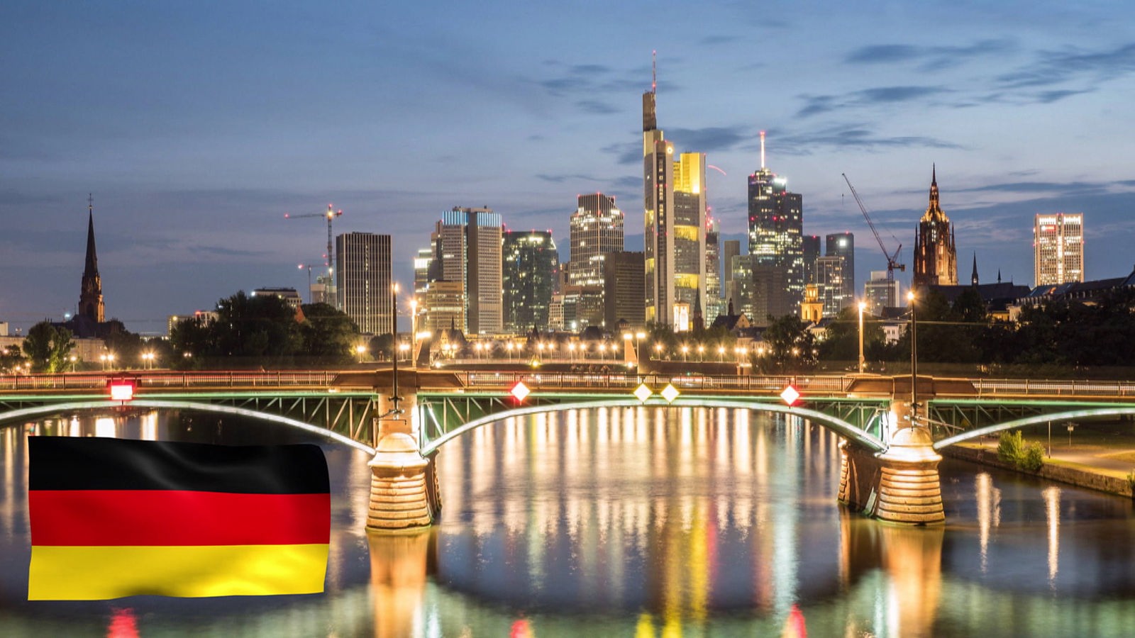 Stadtporträt: Frankfurt in der Dämmerung mit einer Deutschlandfahne links unten.