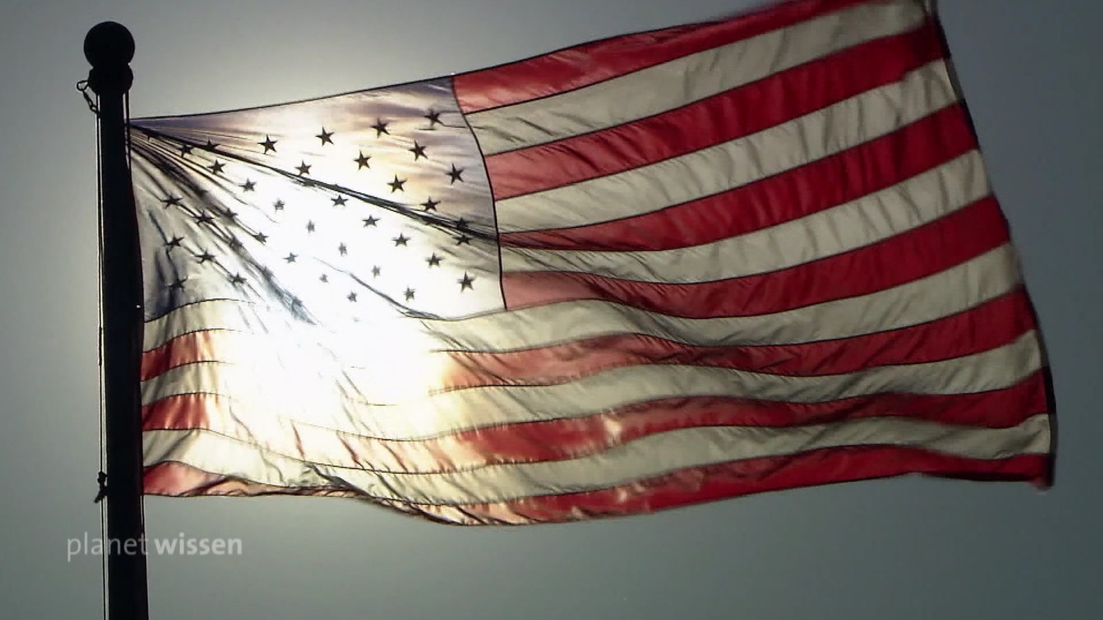 Amerikanische Flagge im Wind, die von der Sonne dahinter angeleuchtet wird.
