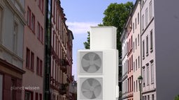 Bildcollage: Eine Wärmepumpe auf der Straße zwischen zwei Altstadt-Häuserreihen.