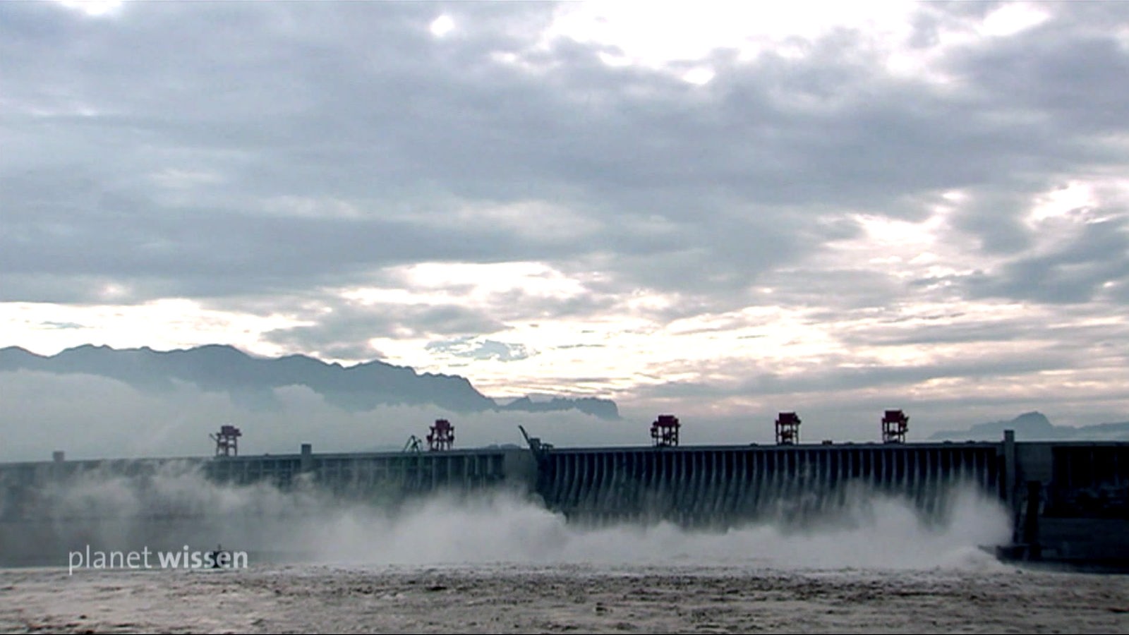 Blick auf die riesige Staumauer des 3-Schluchtenstaudamm in China, aus der Wasser mit hoher Geschwindigkeit strömt.