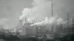 Alte Schwarzweißaufnahme eines Fabrikgeländes voller rauchender Kamine und Schlote.