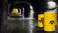 Drei gelbe Tonnen mit Atommüll in einem Tunnel.