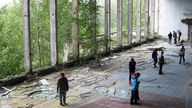Menschen stehen in der verlassenen Sporthalle von Pripyat