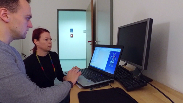 Junger Mann sitzt am Laptop. Darauf ist ein Roboter abgebildet. Ihm zur Seite sitzt Professor Nicole C. Krämer. | Bildquelle: SWR Junger Mann sitzt am Laptop. Darauf ist ein Roboter abgebildet. Ihm zur Seite sitzt Professor Nicole C. Krämer.