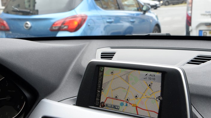 Blick durch die Frontscheibe eines Autos mit Navi auf die Straße