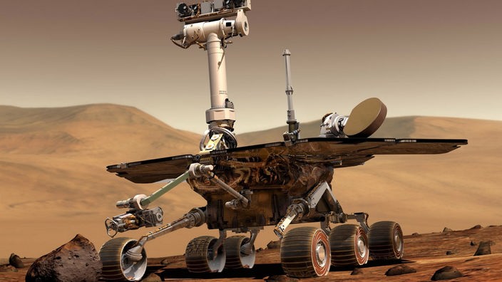 Die Computerillustration zeigt einen Roboter auf vier Rädern, der vor einer kargen Felslandschaft steht.