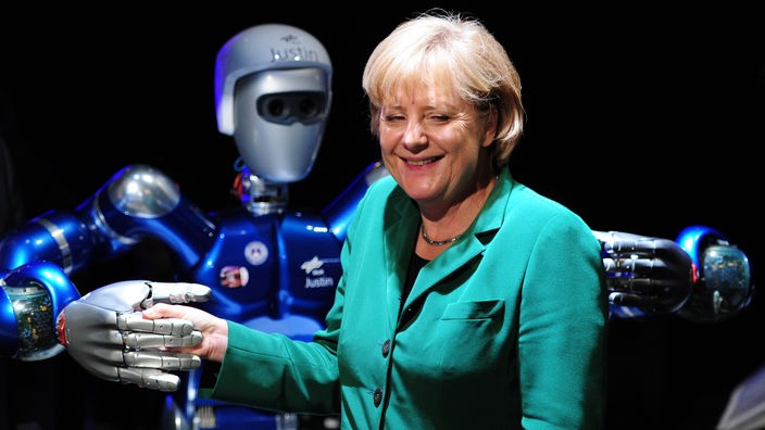 Bundeskanzlerin Angela Merkel schüttelt auf einer Messe einem Roboter die Hand