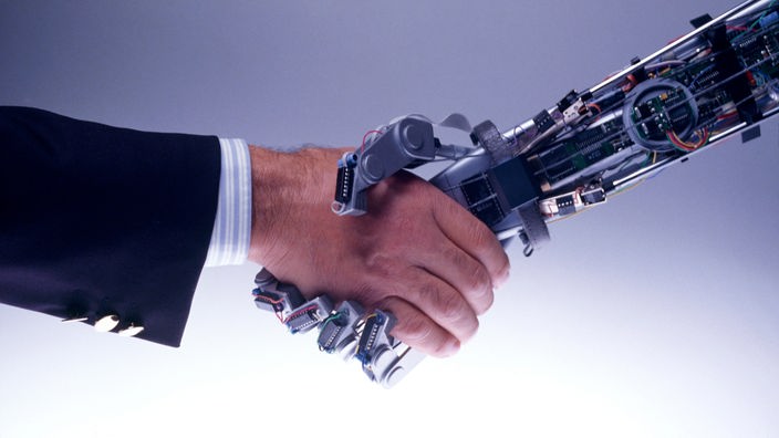 Una mano humana estrecha la mano de un robot 