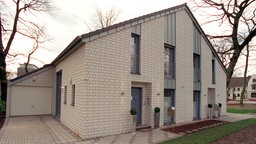 Ein graues Doppelhaus mit Garage.