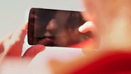 Reporterin Katrin Focke spiegelt sich im Smartphone-Display