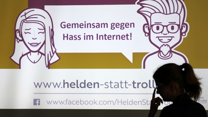 Werbung mit zwei gezeichneten Menschen, dazu der Slogan "Gemeinsam gegen Hass im Internet!" | Bildquelle: picture alliance / Bernd Wüstneck/dpa Werbung mit zwei gezeichneten Menschen, dazu der Slogan "Gemeinsam gegen Hass im Internet!"