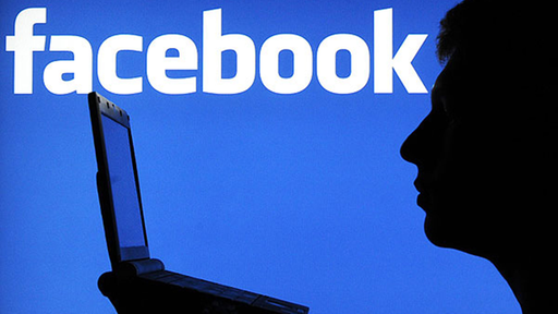 Im Vordergrund ist die Silhouette eines Mannes zu sehen. Er sitzt vor einem Laptop. Im Hintergrund ist das Facebook-Logo groß abgebildet.