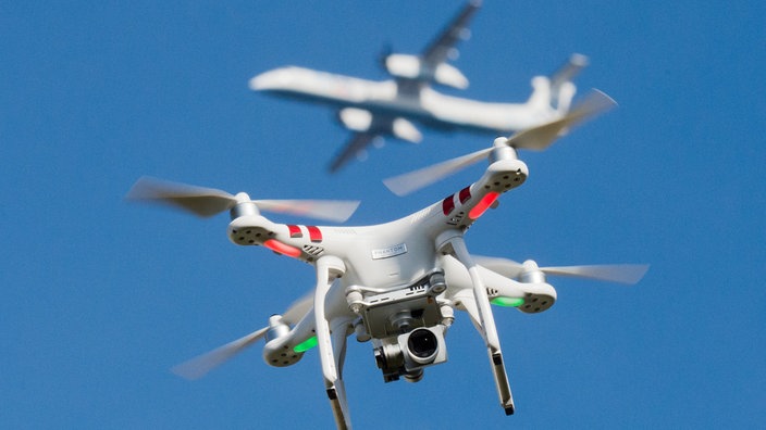 Ein Multikopter fliegt vor einem Passagierflugzeug | Bildquelle: dpa Ein Multikopter fliegt vor einem Passagierflugzeug
