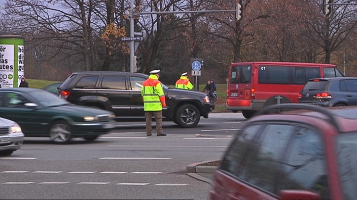 Zwei Polizisten mit Warnwesten im Verkehrschaos. | Bildquelle: SWR Zwei Polizisten mit Warnwesten im Verkehrschaos.