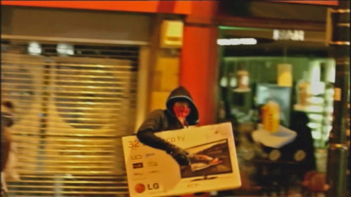 Ein maskierter Plünderer mit einem Plasmabildschirm unter dem Arm.