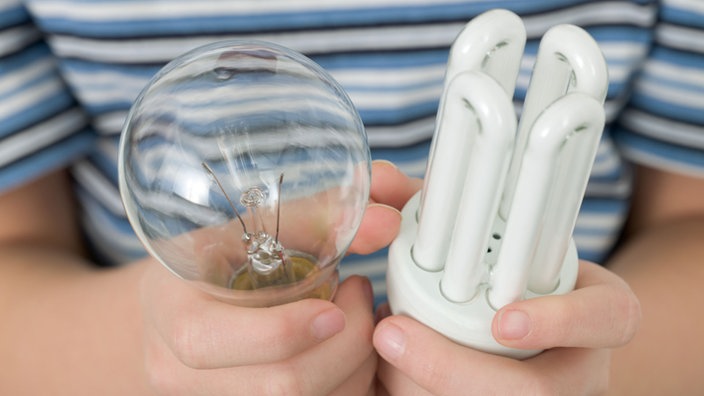 Eine Hand hält eine Glühlampe und eine Energiesparlampe | Bildquelle: WDR / Image Source Eine Hand hält eine Glühlampe und eine Energiesparlampe