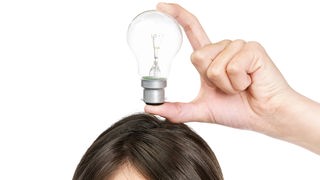 Eine Frau hält sich eine Glühbirne über den Kopf