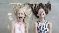 Zwei Mädchen mit Haaren an die Wäscheleine gesteckt.