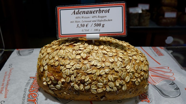In der Auslage einer Bäckerei liegt ein Brot mit einem Schild "Adenauerbrot" | Bildquelle: picture alliance / ZB In der Auslage einer Bäckerei liegt ein Brot mit einem Schild "Adenauerbrot"