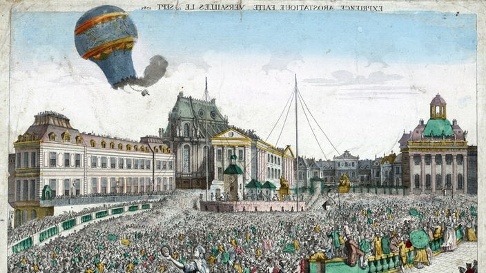 Schwarzweiß-Stich: Eine große Menschenmenge auf einem Platz, in der Luft schwebt ein Ballon