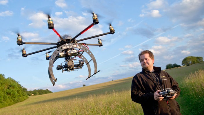 Ein Mann steuert mit einer Fernsteuerung eine Drohne 