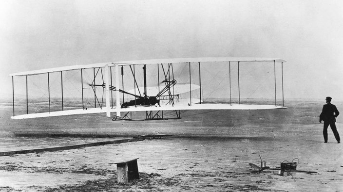 Ein Doppeldecker fliegt knapp über einen Sandboden | Bildquelle: imago Ein Doppeldecker fliegt knapp über einen Sandboden