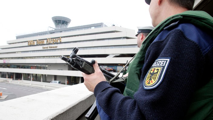 Bundespolizist steht mit einer Maschinenpistole auf einem Flughafengelände