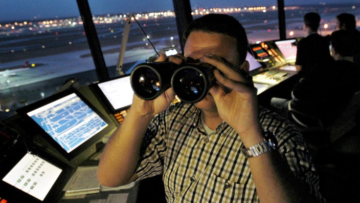 Fluglotse mit Fernglas | Bildquelle: dpa/Alexander Heimann Fluglotse mit Fernglas