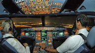 Zwei Piloten im Cockpit eines großen Flugzeuges bei Nacht