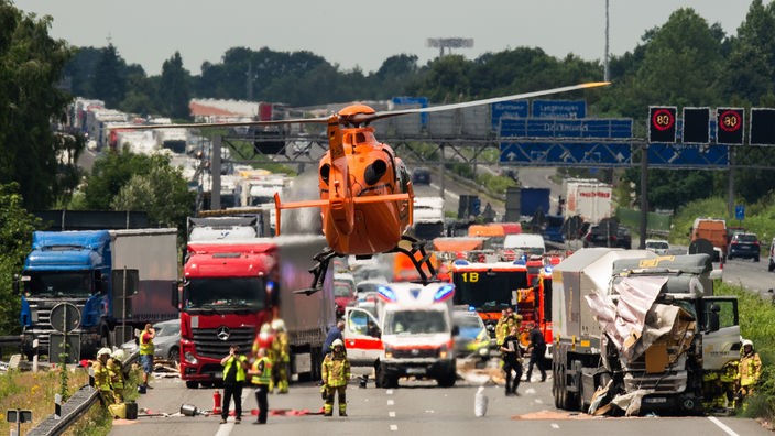 Ein orangener Hubschrauber landet bei einer Unfallstelle auf der Autobahn.
