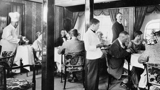 Schwarz-Weiß-Foto: Speisesaal in einem Luftschiff mit Tischen und Stühlen