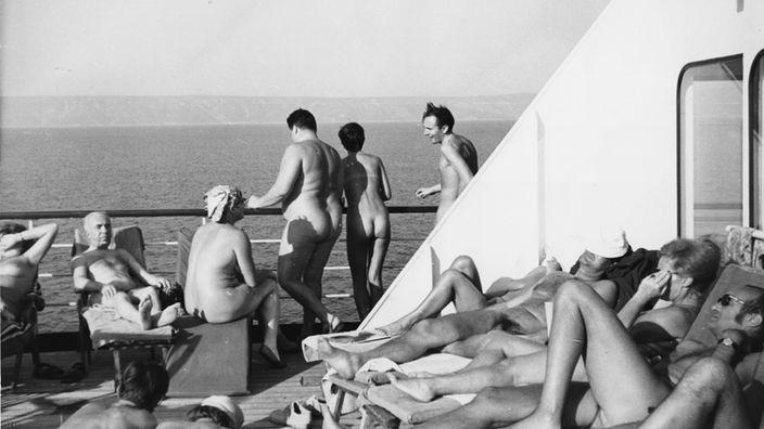 Schwarz-weiß-Foto: Naturisten liegen an Deck eines Kreuzfahrtschiffes