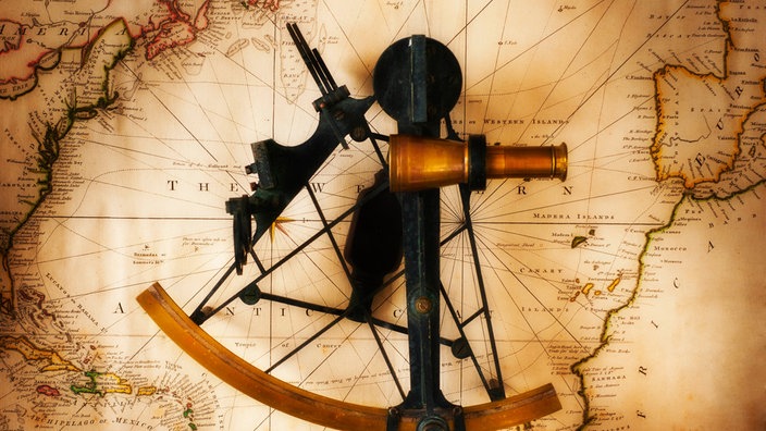  Sextant, Zirkel und Kompass liegen auf einer alten Weltkarte