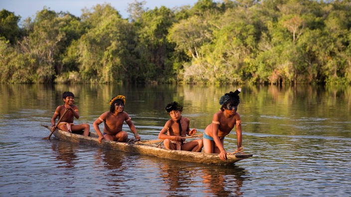 Einbaum mit vier Xingu-Indianern auf dem Amazonas. Der Letzte im Boot paddelt