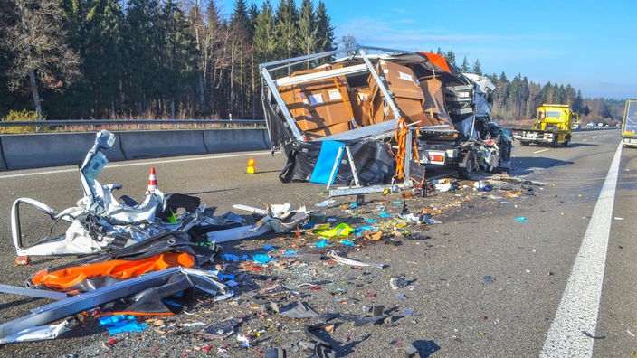 Nach einem schweren Verkehrsunfall liegen Trümmerteile und ein zerstörtes Fahrzeug auf der Autobahn