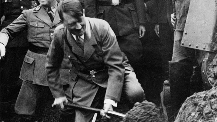 Eine Schwarzweiß-Aufnahme vom 23. September 1933: Adolf Hitler umringt von Offizieren in Uniform beim ersten Spatenstich zum Bau der Autobahn Frankfurt-Mannheim