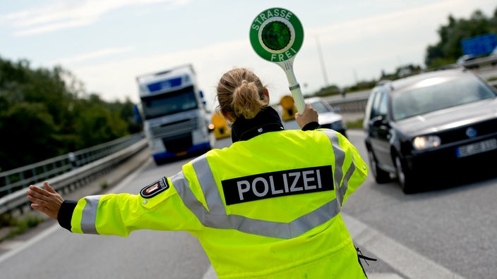 Eine Polizistin winkt einen Lastwagen von der Autobahn