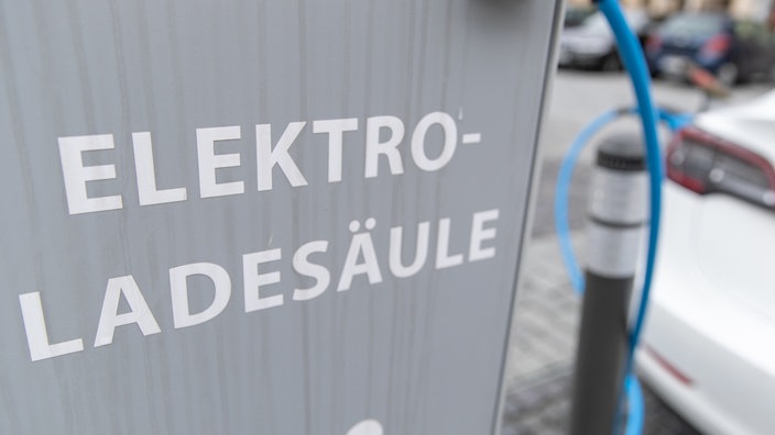 Graue Elektro-Ladesäule. Im Hintergrund weißes Elektroauto | Bildquelle: WDR/dpa/Friso Gentsch Graue Elektro-Ladesäule. Im Hintergrund weißes Elektroauto