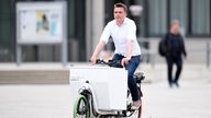 Mann fährt ein weißes E-Lastenrad 