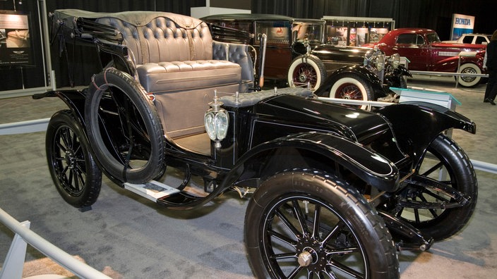 Ein schwarzer Oldtimer steht in einer Museumshalle. Er hat beige Ledersitze und ist offen, wie eine Kutsche | Bildquelle: dpa/Jim West Ein schwarzer Oldtimer steht in einer Museumshalle. Er hat beige Ledersitze und ist offen, wie eine Kutsche