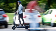 Frau auf E-Roller fährt auf der Straße 