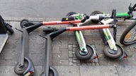 Verschiedene E-Roller liegen umgekippt auf dem Bürgersteig 
