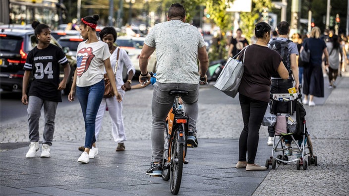 Radfahrer fährt auf einem Gehweg zwischen Passanten