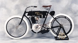 Ein schwarzes Fahrrad mit einem Ein-Zylinder-Motor, der mit dem Hinterreifen über einen Riemen verbunden ist